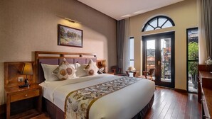 Een hotelkamer met een groot bed, een houten hoofdeinde en uitzicht op de omgeving door een glazen deur.