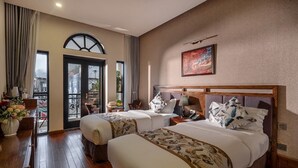 Habitació d'hotel amb dos llits, zona de menjador i un balcó.