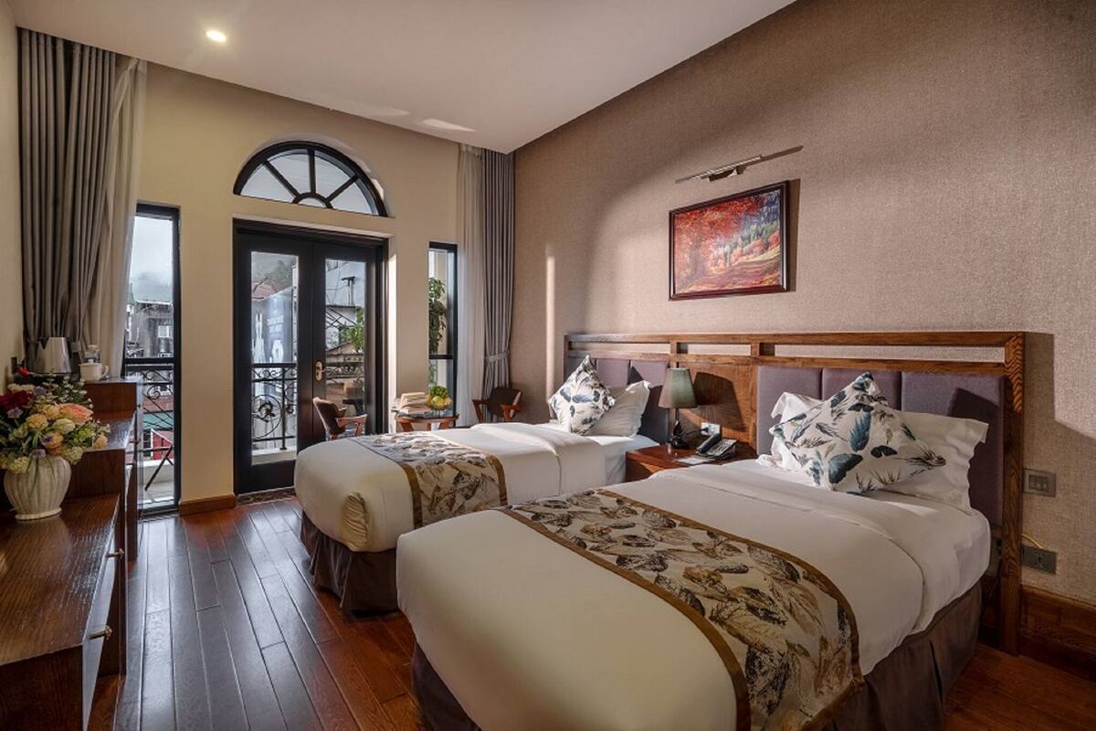 Ein Hotelzimmer mit zwei Betten, einem Essbereich und einem Balkon.