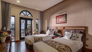 Een hotelkamer met twee bedden, een zithoek en een balkon.
