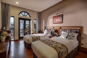 Een hotelkamer met twee bedden, een zithoek en een balkon.