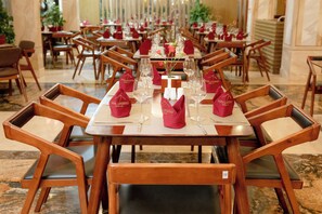 Een restaurant met houten stoelen en tafels, elk met een rode servet en glazen.