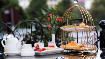 A table set with a teapot, cups, a plate with strawberries, a small vase with flowers, and a decorative birdcage with pastries.