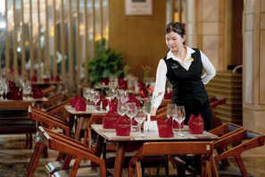 Een restaurantomgeving met gedekte tafels, elk met een rode servet en een glas water.