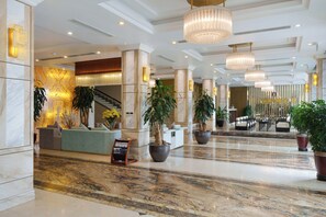 A spacious lobby with marble flooring, a reception desk, seating areas, and large potted plants. - Canvas Sapa Legend Hotel (Ho Chi Minh Municipality)