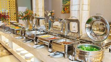 A buffet setup with multiple food stations, each with a metal serving tray and a variety of dishes.