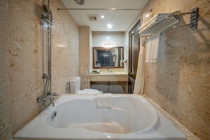 Een badkamer met een groot bad, een wastafel, een spiegel en een handdoekhouder.