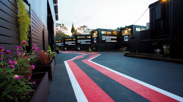 A parking area with marked lanes leading to container houses labeled 'Villa Kurokawa'. - Container House Villa Kurokawa　 (Minamioguni)