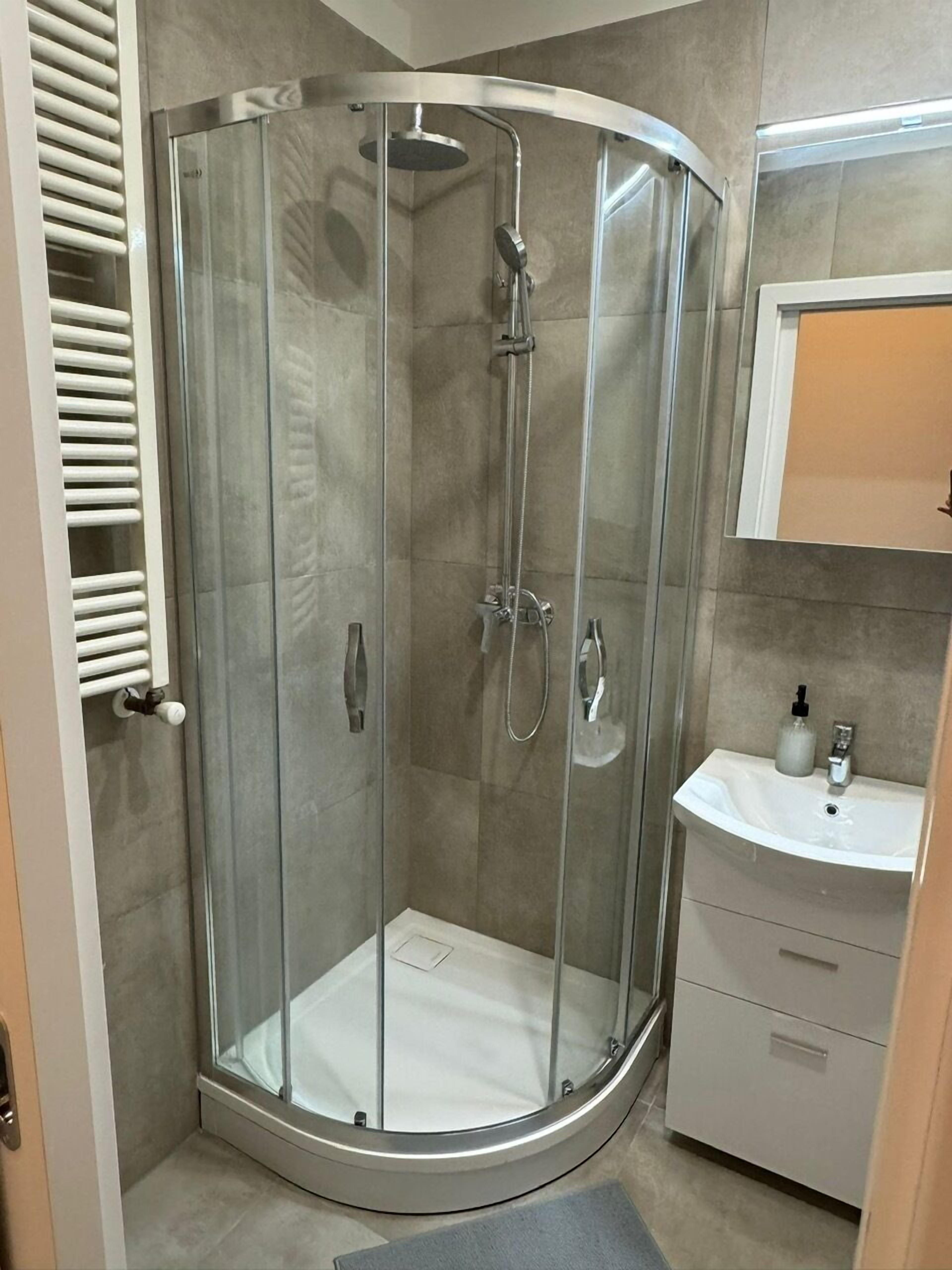 A glass-enclosed shower with a white sink and a mirror above it.