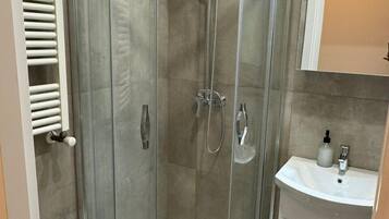 A glass-enclosed shower with a white sink and a mirror above it.