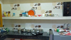 A kitchen with a black countertop, a red trash bin, and a coffee machine. - Om home stay (Faizabad)