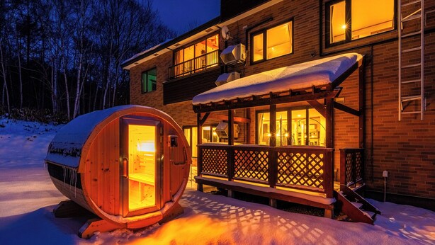 A wooden cabin with a glass door, a covered deck, and a snow-covered ground. - THE ELYSIAN RETREAT (Otaru)