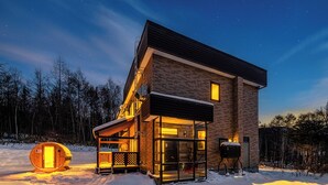 A modern house with a glass-enclosed porch, a wooden cabin, and a barbecue area. - THE ELYSIAN RETREAT (Otaru)