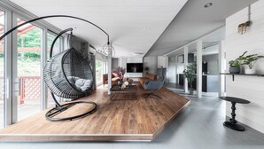 A modern living room with a hanging chair, a coffee table, and a TV. - THE ELYSIAN RETREAT (Otaru)
