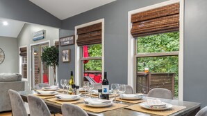 Un comedor con una mesa larga dispuesta para seis personas, rodeada de sillas grises tapizadas.