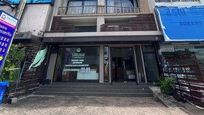 Un immeuble à plusieurs étages doté d’une façade moderne en verre, d’un logo bien visible représentant une feuille verte, et d’une entrée au niveau du sol avec une enseigne indiquant « Leram ».