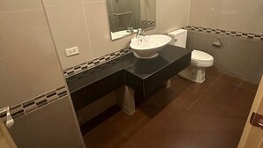 Une salle de bain moderne avec un grand miroir, un lavabo et des toilettes.