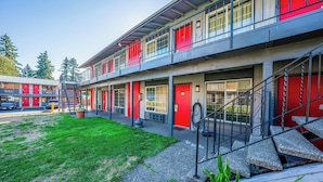 A multi-story building with red doors and a staircase leading to the upper floor.