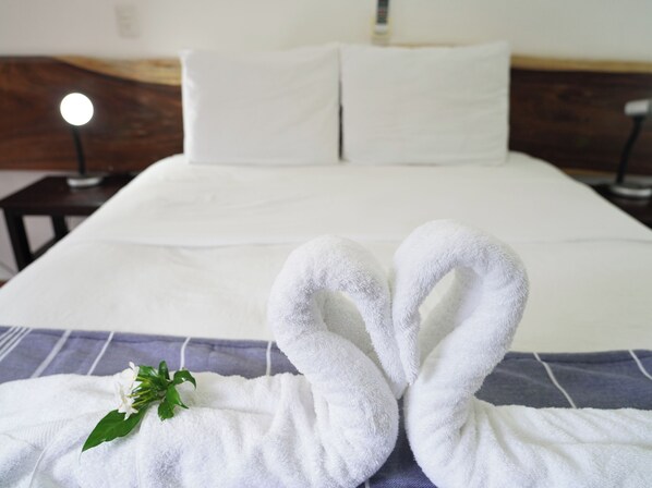 A neatly made bed with white linens and two towels arranged in a heart shape on the bed. - Hotel Ingigante Poolside Room (El Gigante)