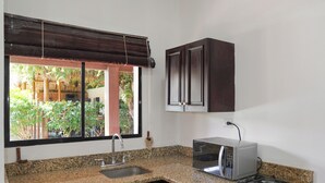 A kitchen with granite countertops, a built-in microwave, a stove, a sink, and dark wooden cabinets. - Hotel Ingigante Poolside Room (El Gigante)