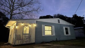 Une petite maison de plain-pied dotée d’un porche éclairé par des guirlandes lumineuses.