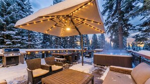 Eine Terrasse im Freien mit Korbmöbeln, einem Whirlpool und Lichterketten.