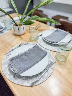 Una mesa con platos, cubiertos y una copa.