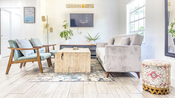 A living room with a sofa, chairs, a coffee table, a TV, and a ceiling fan.