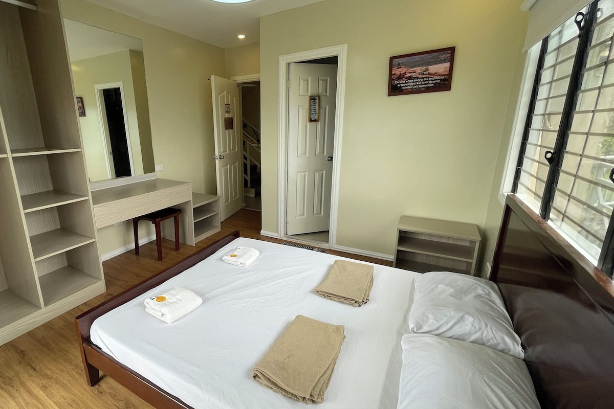 Une chambre d’hôtel avec un lit, une armoire, un bureau et un miroir.