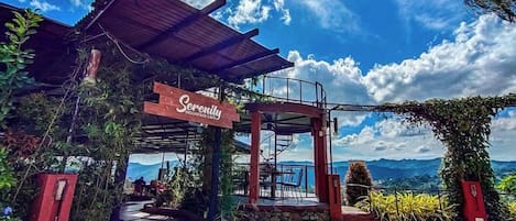 A mountain cafe named 'Serenity' with outdoor seating and a view of the mountains.