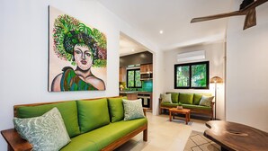 A modern living room with a green sofa, a wooden coffee table, and a painting on the wall.