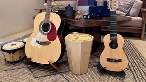 A room with a wooden coffee table, a couch, and two guitars on stands.