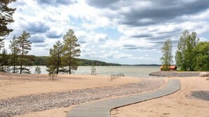 Ein Strand mit einer Holzpromenade, die zu einer kleinen Holzhütte führt.