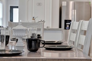 A modern kitchen with a long dining table, white chairs, and various kitchen appliances. - New - 3 bed 2 Bath house in Magnolia with Fast Wifi- Garage Parking (Magnolia)
