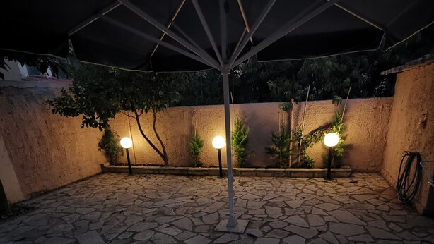 An outdoor patio with stone flooring and a central umbrella structure. - RENT HOUSE ROOMS KALAMATA  (Agios Dionisios)
