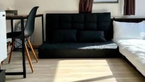 A small, well-lit room with a bed, a sofa, a desk, and a chair. - Gracious Higashi Shinjuku (Tokyo)
