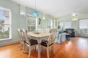 Un espace repas comprenant une table et des chaises, un lustre et un ventilateur de plafond.