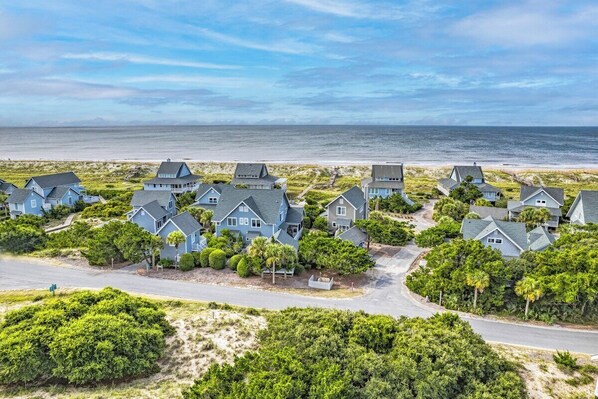 A coastal residential area with houses, a road, and a beach.