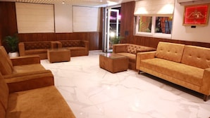 Una sala de estar moderna con un sofá marrón, una mesa de centro de vidrio y un ventanal con vistas.