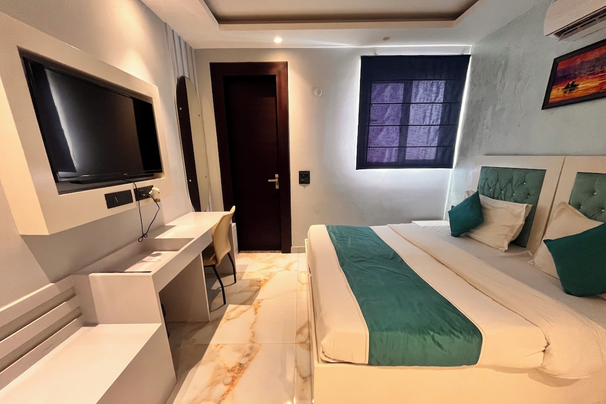Una habitación de hotel moderna con cama, escritorio, televisión y ventana.