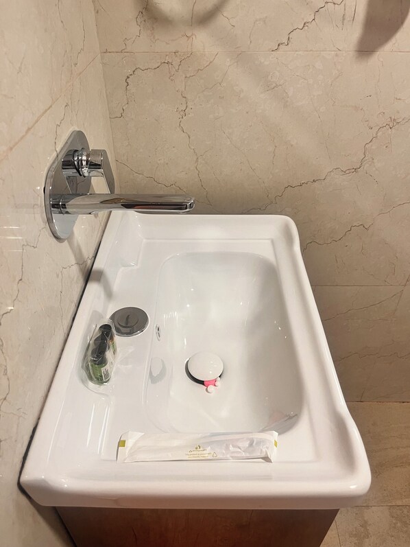 A bathroom sink with a mirror, faucet, and a bottle of hand soap. - Hotel VS Residency Medanta (Gurugram)
