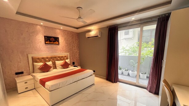 Un dormitorio moderno con una cama grande, un ventilador de techo y vistas a un balcón con plantas en macetas.
