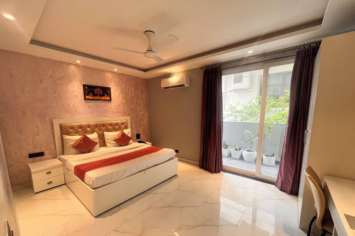 Un dormitorio moderno con una cama grande, un ventilador de techo y vistas a un balcón con plantas en macetas.