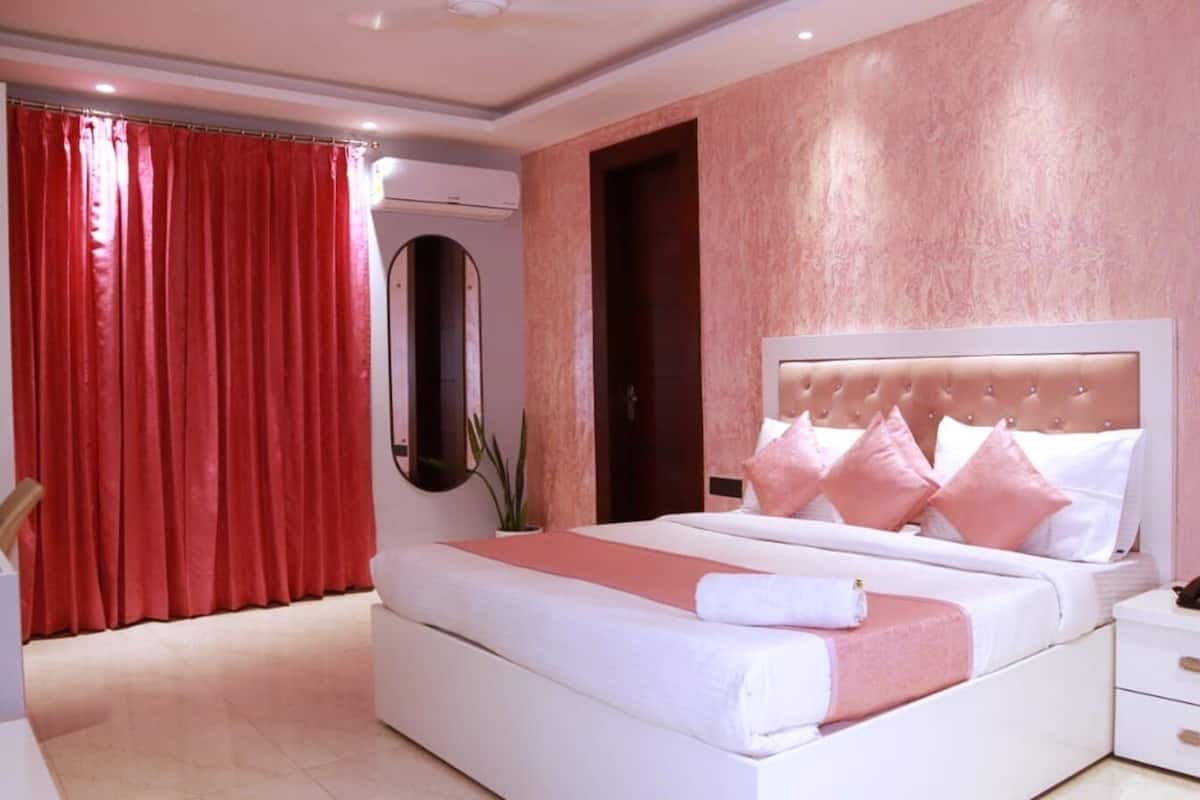 Un dormitorio con cama, mesitas de noche, un espejo y una cortina roja.