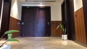 Un pasillo con dos puertas de madera oscura, una lámpara en el techo y una planta en maceta.