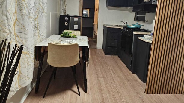 Une cuisine de taille réduite avec un coin repas, un plancher en bois et un luminaire au plafond.