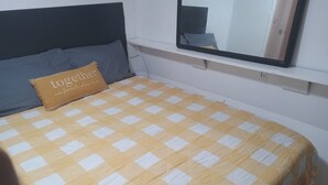Un lit avec une couvre-lit à carreaux jaunes et blancs, un oreiller marron orné de texte et une tête de lit sombre.