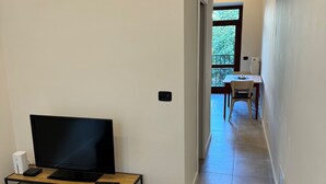 A hotel room with a bed, a TV, a desk with a computer, and a view of a balcony. - Cool Vitkova apartment near Florenc with small balcony (Hlavní mesto Praha)