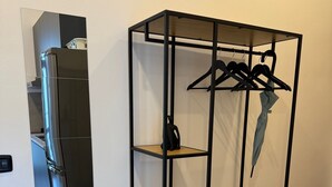 A metal shelving unit with wooden shelves, a black hanger, and a light blue umbrella. - Cool Vitkova apartment near Florenc with small balcony (Hlavní mesto Praha)