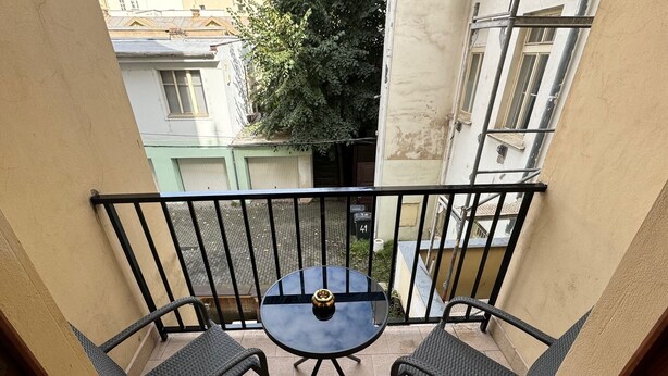 A small balcony with a round table and two chairs, surrounded by a black metal railing. - Cool Vitkova apartment near Florenc with small balcony (Hlavní mesto Praha)